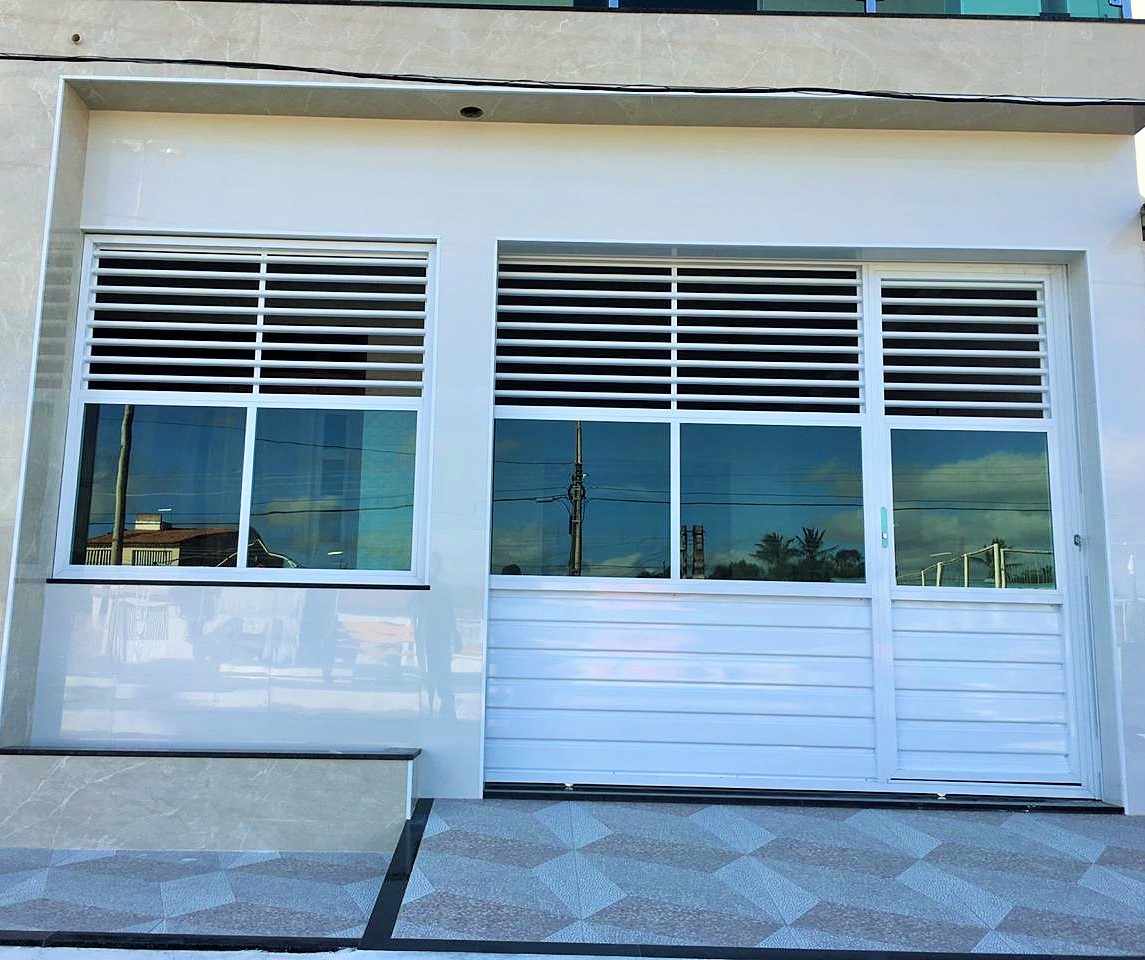 Portão em alumínio branco. Modelo : Vazado na parte de cima, com vidro incolor , e parte fechada com lambril liso na horizontal. Com acoplado, de correr. Com grade fixa.